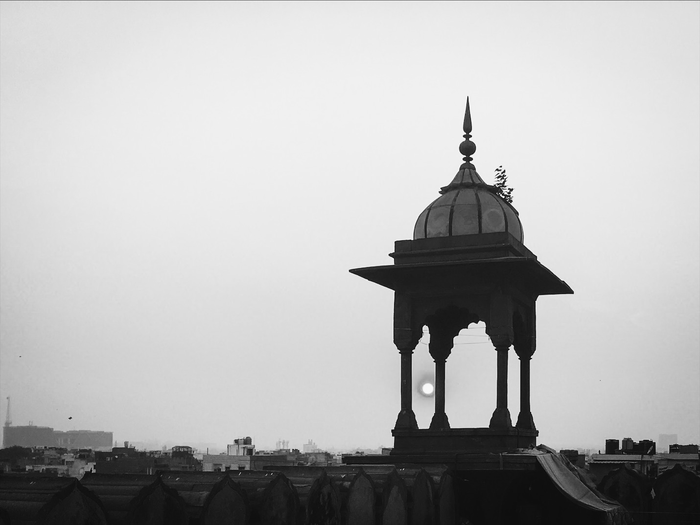 A silhouetted domed pavilion above a city skyline